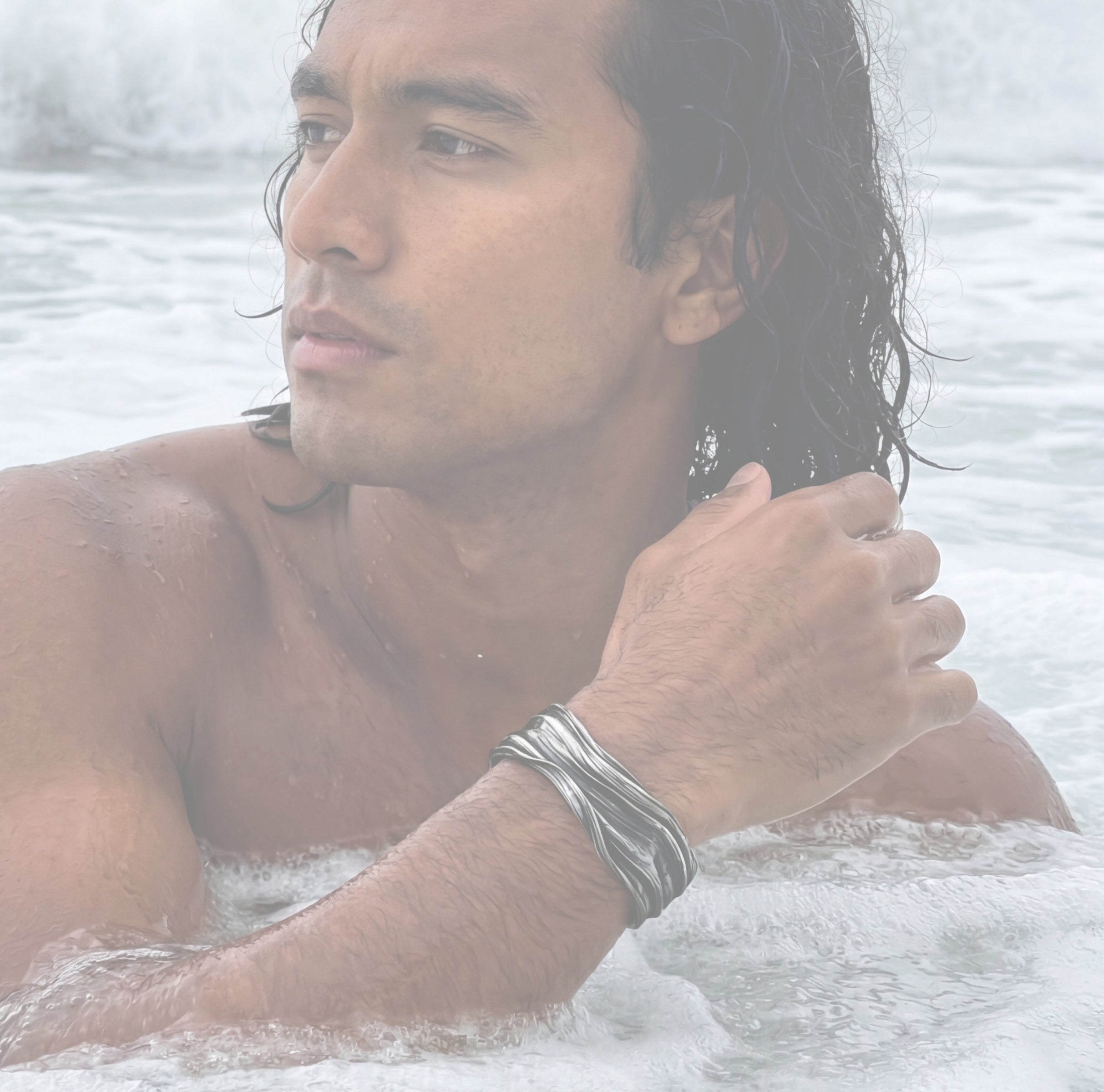 a man in the surf wearing the Meander Cuff Bracelet in sterling silver inspired by meandering waves by jewelry sculptor Michelle Hoting