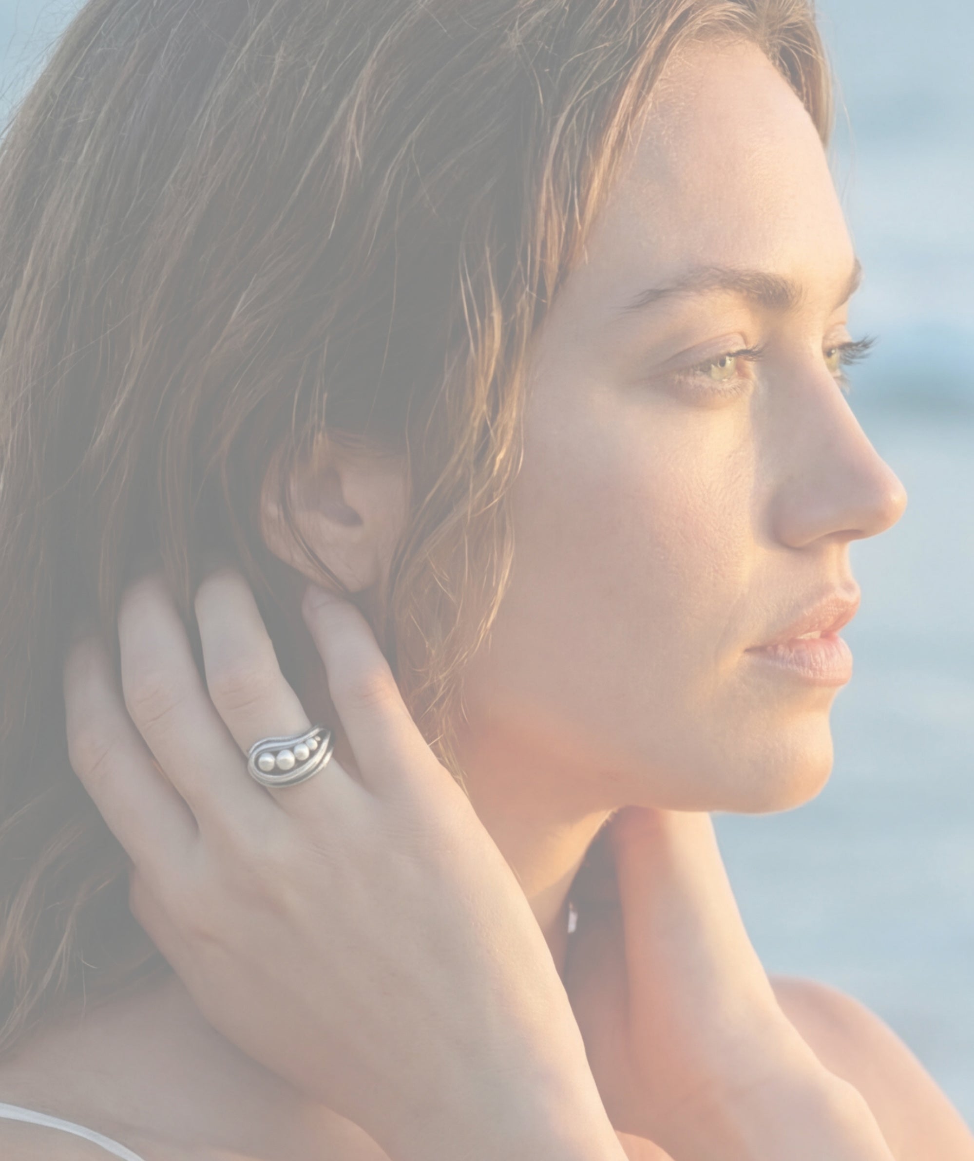 a woman looking at the water wearing the sea foam pearl ring by michelle hoting created using mitsuro himkime