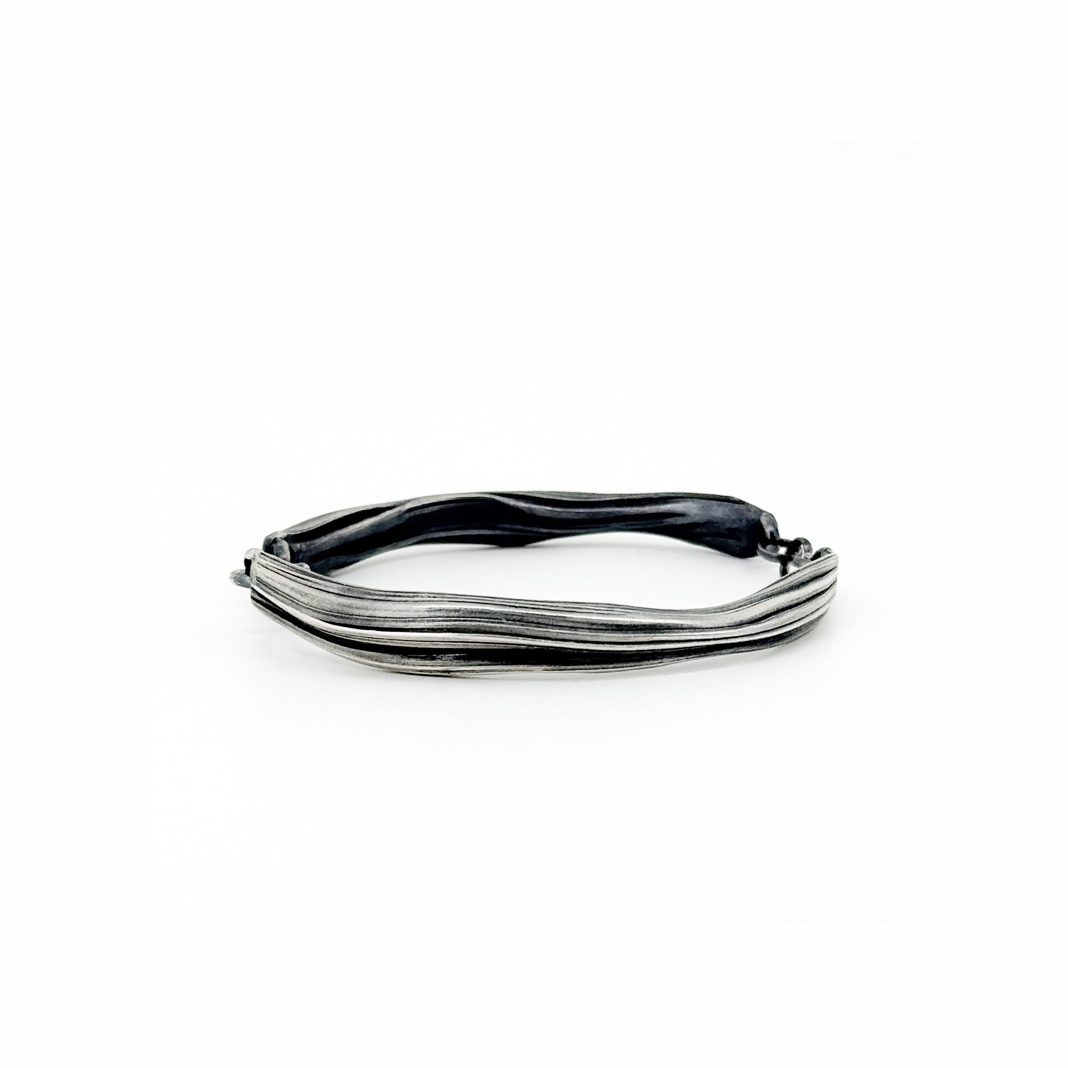 a silver  bracelet with a sculptural strata like  pattern hand fabricated by jewelry artist Michelle Hoting using the Mitsuro Hikime technique