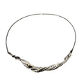 a twisting silver necklace with pearls that look like sea foam  along the edge of waves washing up on the shore
