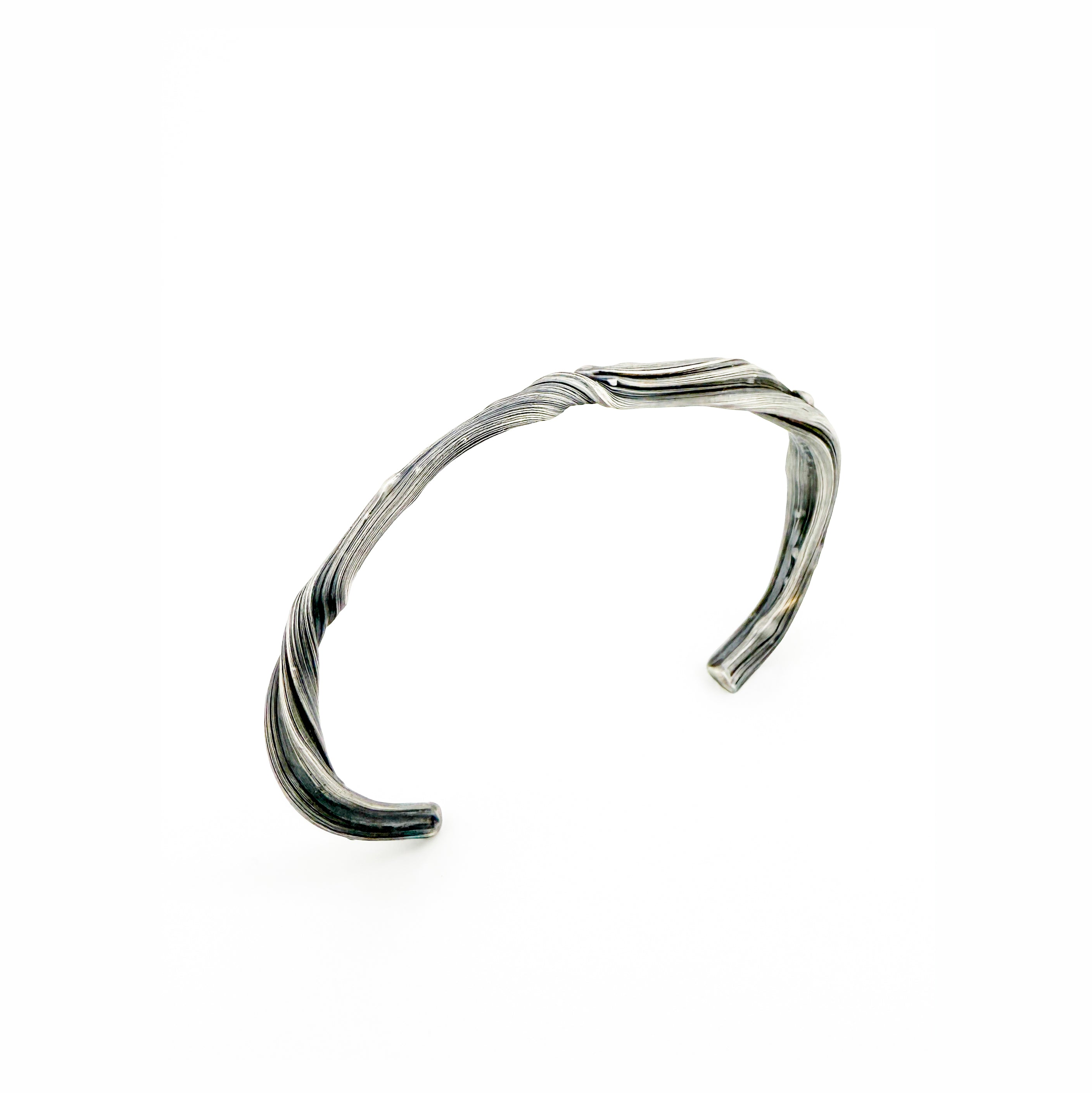 a sterling silver cuff bracelet made to resemble waves washing onto a rocky shoreline by sculptural jeweler michelle hoting using mitsuro hikime
