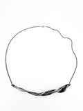 a sterling silver necklace with a sculptural wave like twisting pattern.