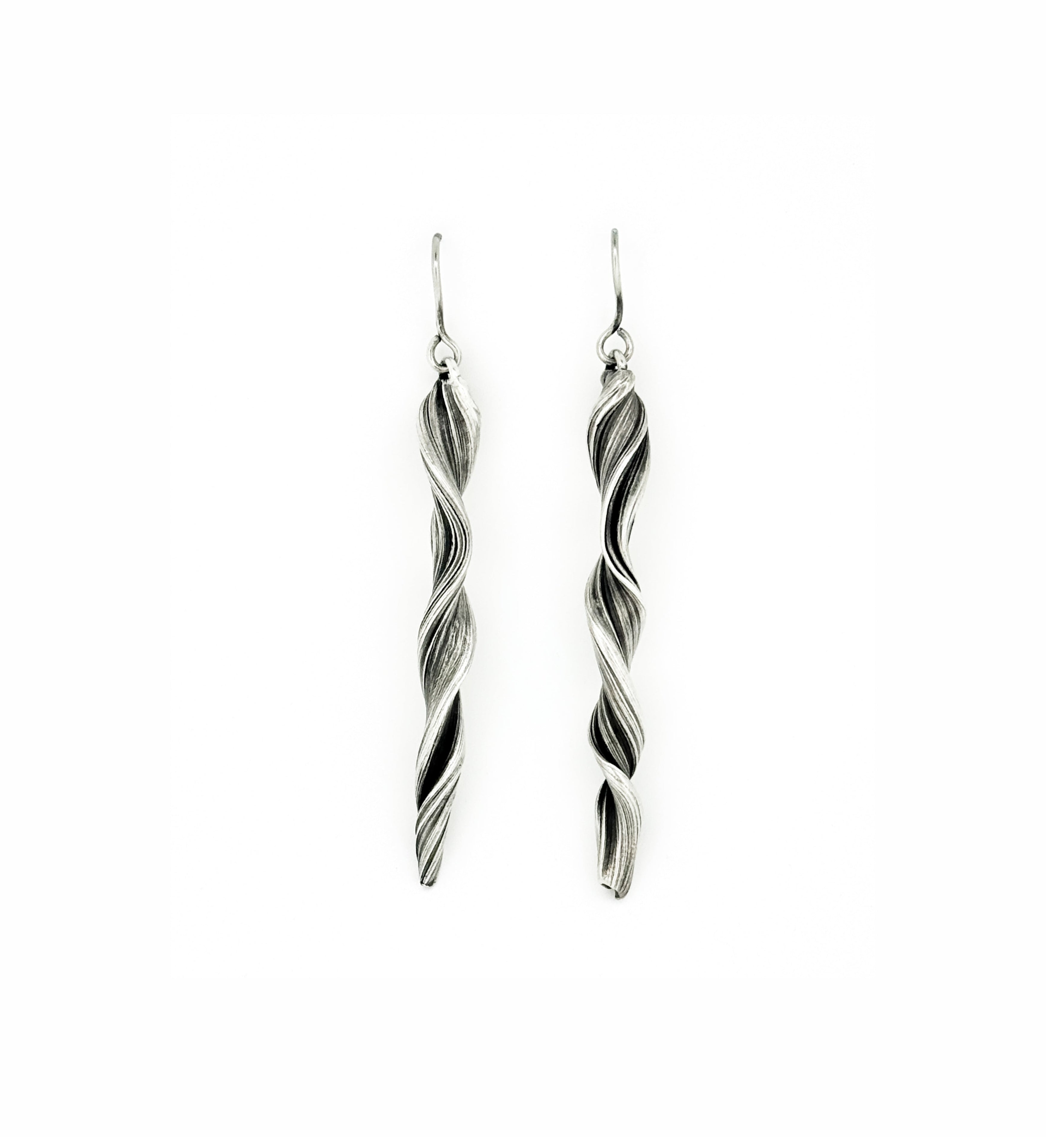 a pair of sterling silver earrings that resemble waves folding and forming.