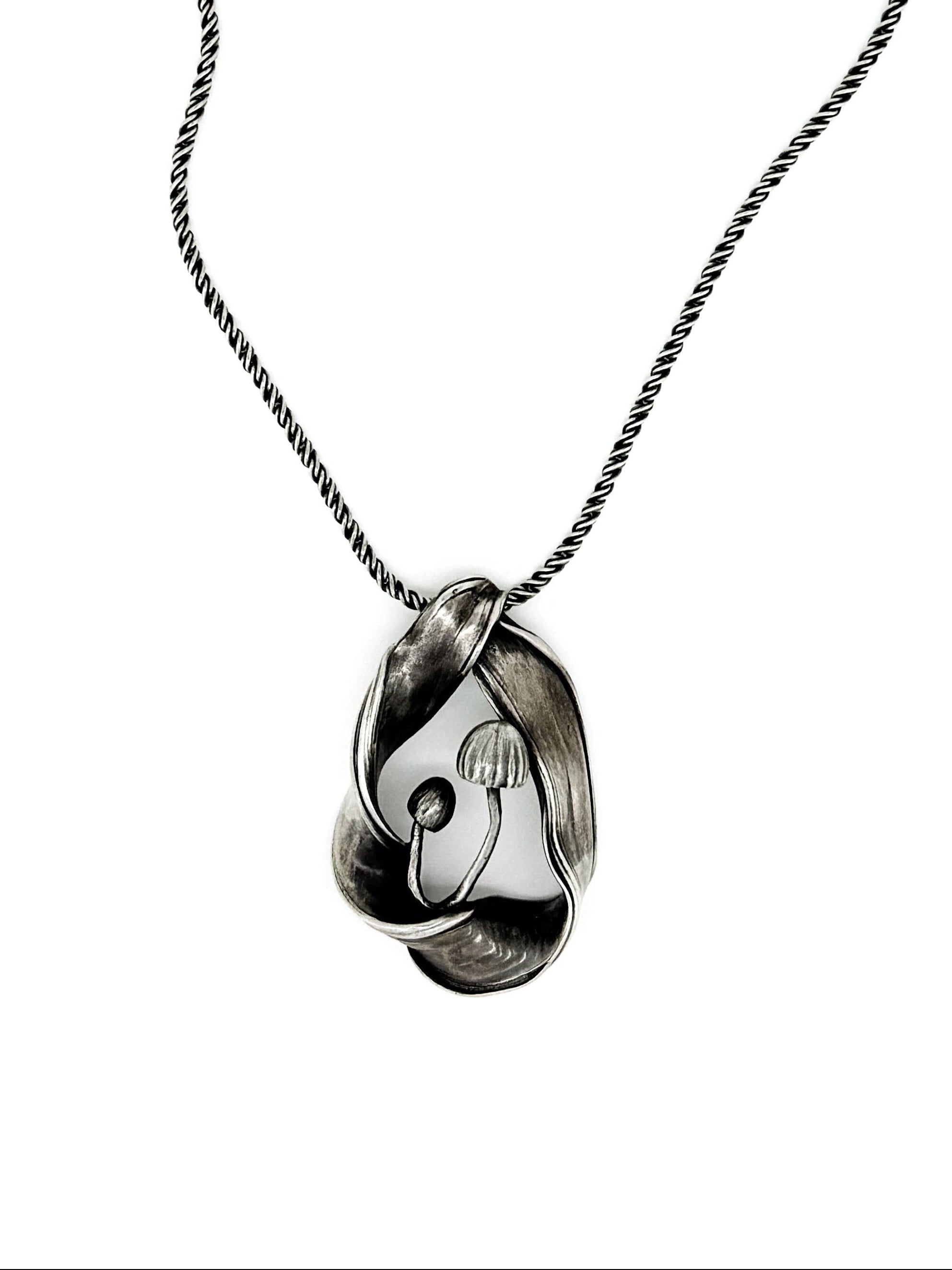 silver pendant with mushrooms surrounded by a undulating frame