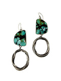earrings of sculptural, circular hoops hang from hand cut turquoise.